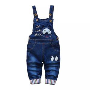A baby wearing overalls with an animal design.