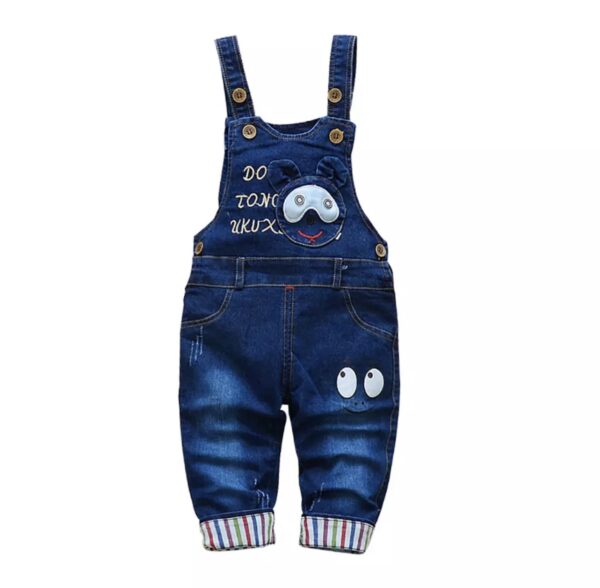 A baby wearing overalls with an animal design.